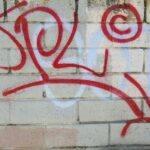 a red and white graffiti on a white wall