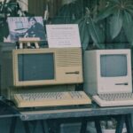 Retro Apple computers with keyboards displayed in a Tokyo store window, showcasing early tech design.